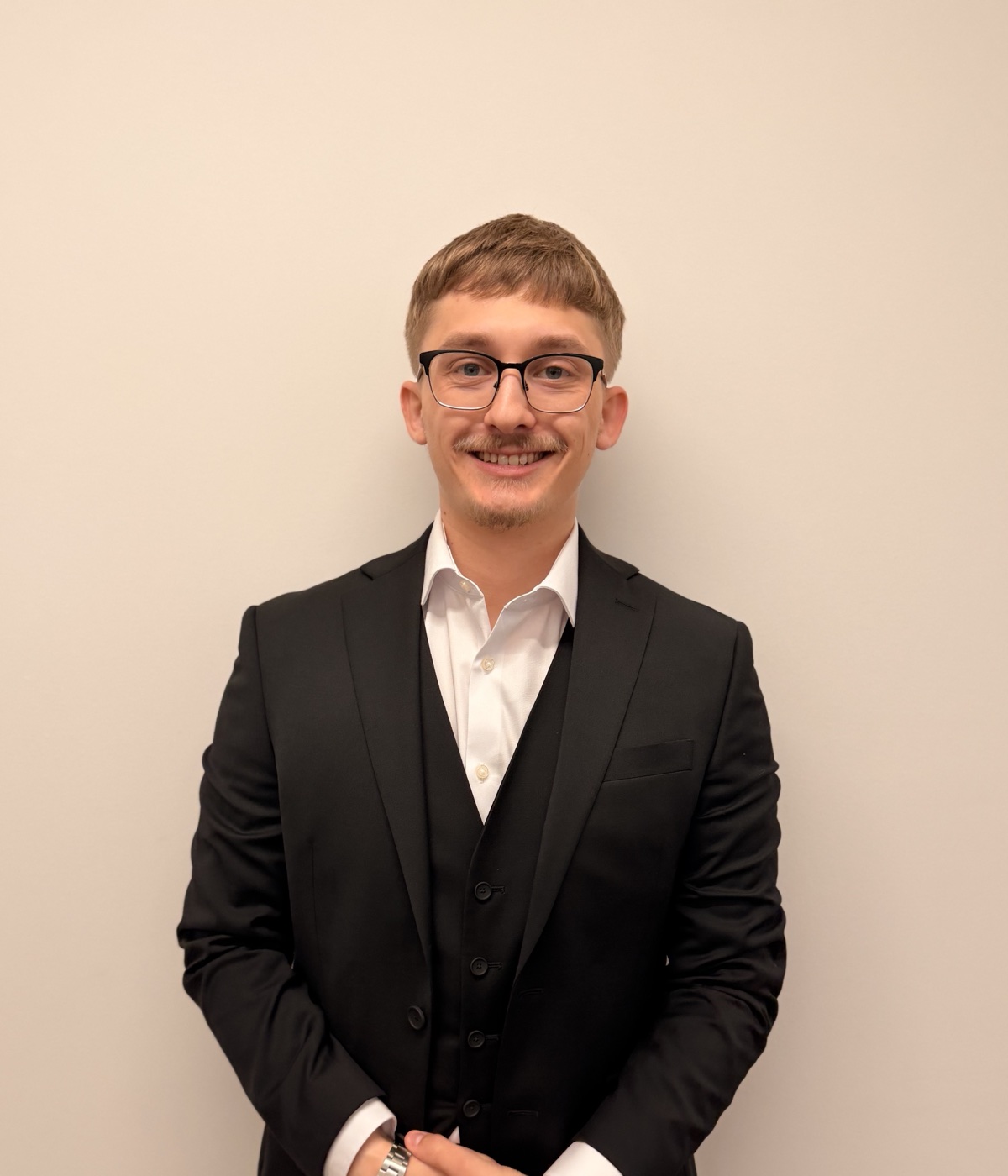 Daniel Ruh standing in a black suit, smiling